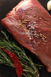 Piece of raw beef meat, rosemary, spices and chili pepper on table, flat lay