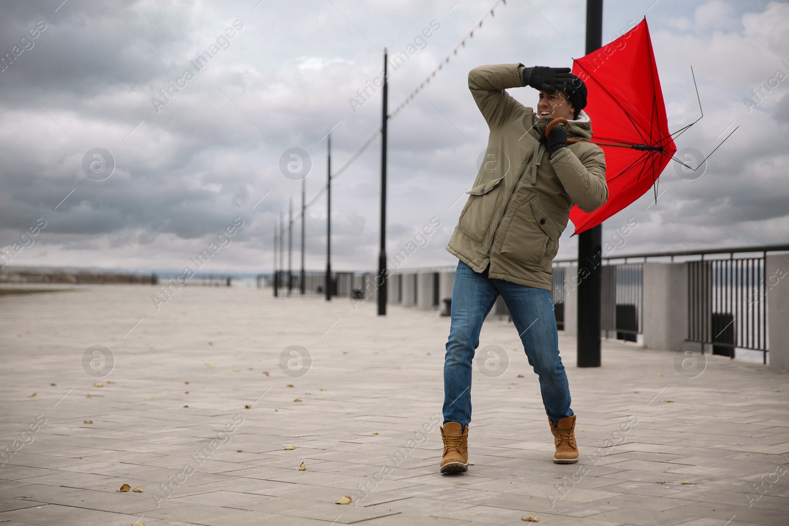 Photo of Man with red umbrella caught in gust of wind outdoors