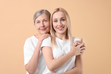 Photo of Family portrait of young woman and her mother on beige background