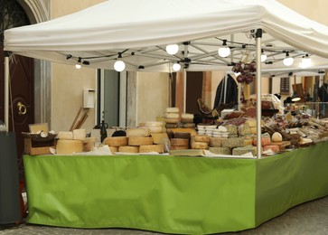 Street market stall with fresh cheese heads and other products near building