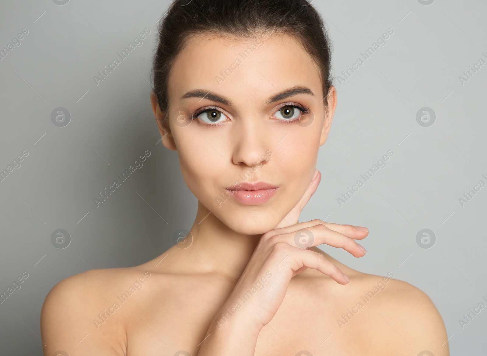 Photo of Young woman with beautiful makeup on grey background. Professional cosmetic products