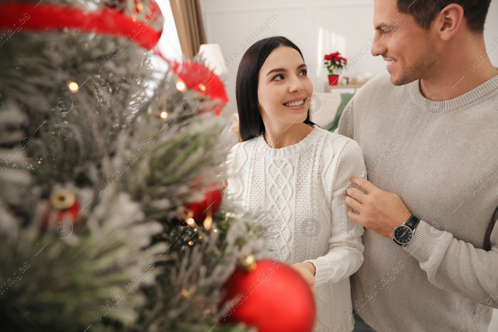 Photo of Happy couple decorating Christmas tree at home