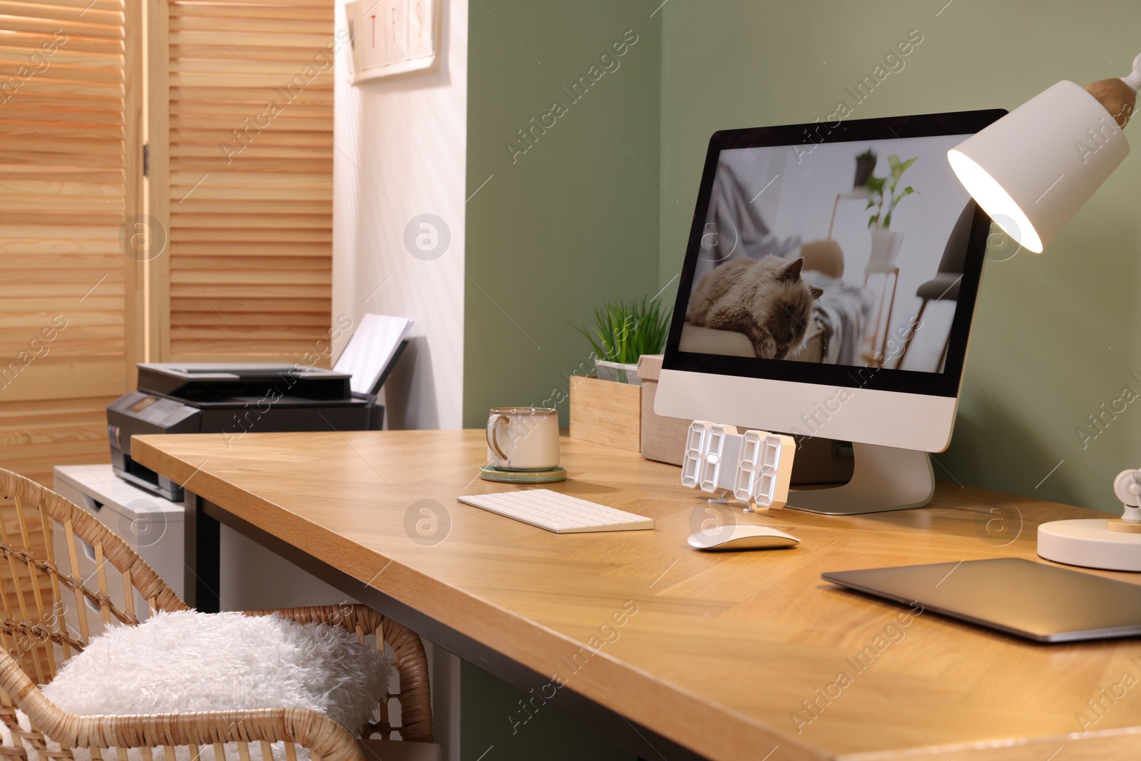 Photo of Stylish workplace with computer, laptop and lamp near olive wall at home