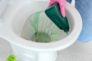 Photo of Woman cleaning toilet bowl in bathroom