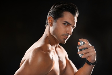 Photo of Handsome young man using perfume on black background