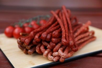 Photo of Tasty dry cured sausages (kabanosy) on wooden table, closeup
