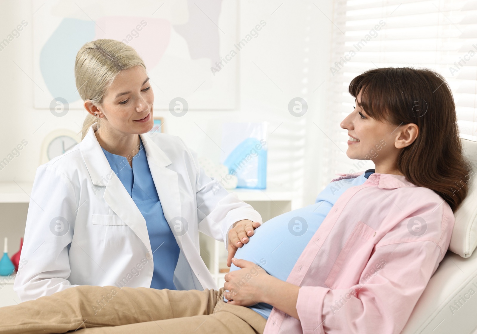 Photo of Pregnancy checkup. Doctor examining patient's tummy in clinic