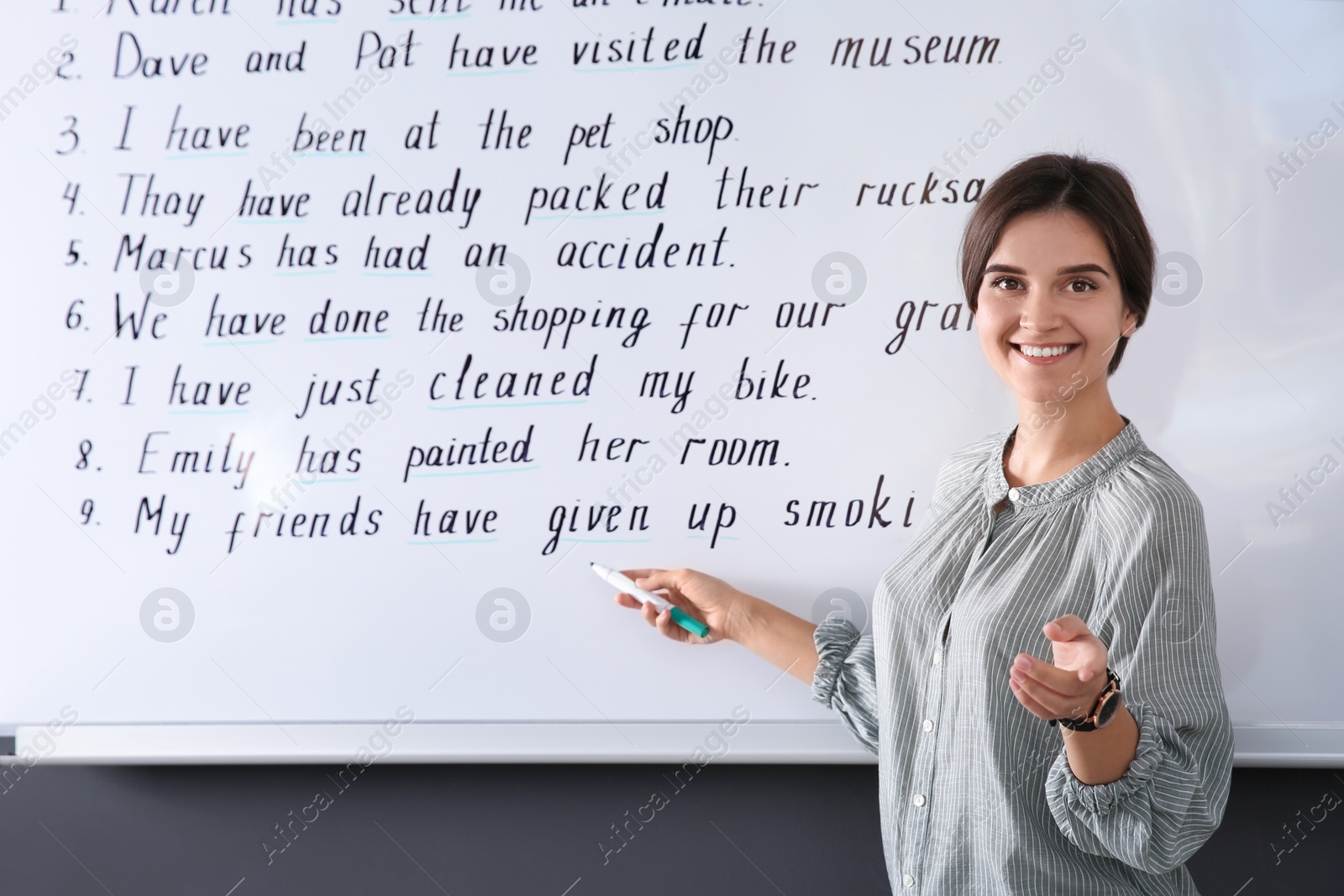 Photo of Happy English teacher near whiteboard at lesson