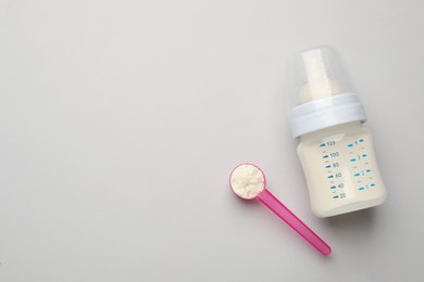 Photo of Feeding bottle with infant formula and powder on light background, flat lay. Space for text