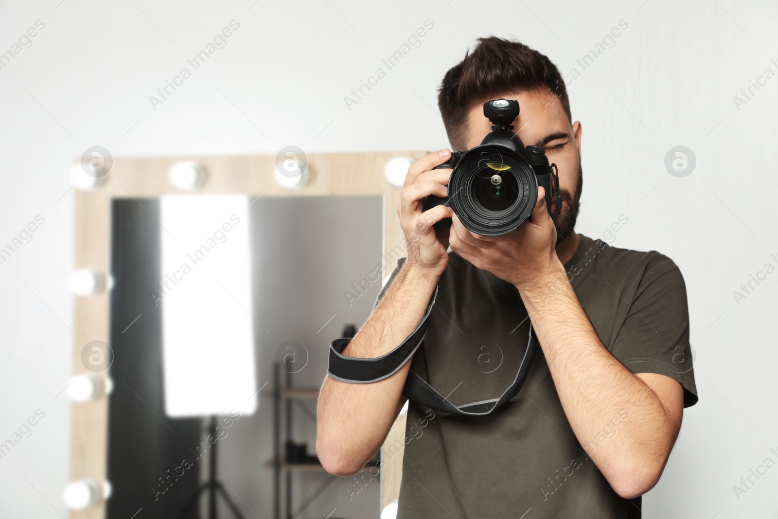 Photo of Young man with professional camera in photo studio. Space for text