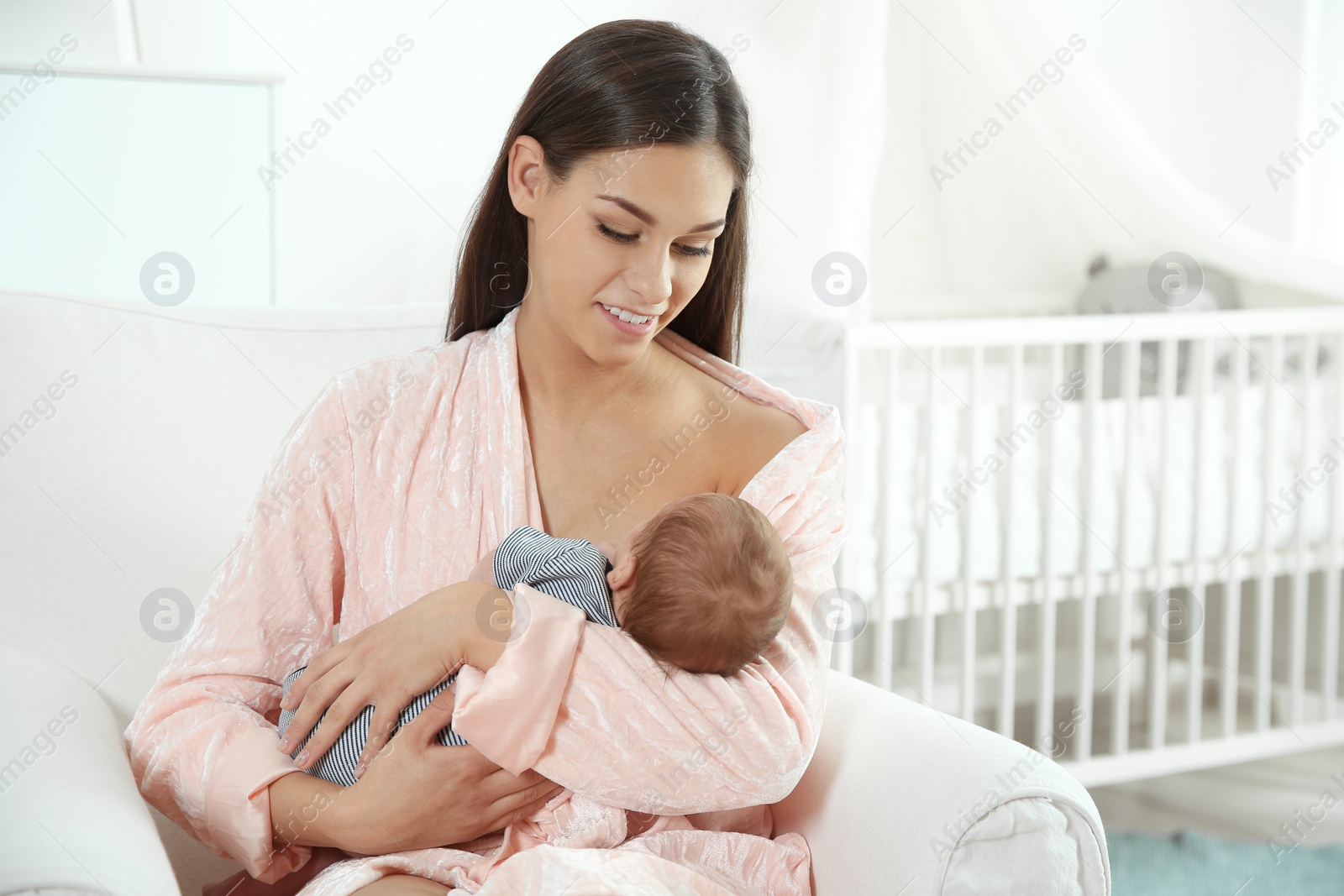 Photo of Young woman breastfeeding her baby in nursery. Space for text