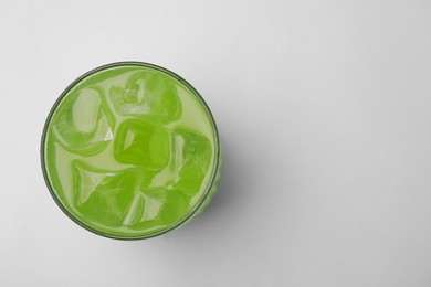 Glass of delicious iced green matcha tea on white background, top view. Space for text