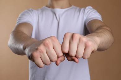 Man showing fists with space for tattoo on beige background, selective focus