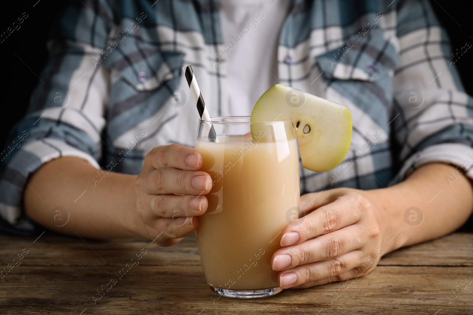 Photo of Woman with tasty pear juice at wooden table, closeup