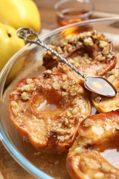 Photo of Tasty baked quinces with walnuts and honey in bowl on table, closeup