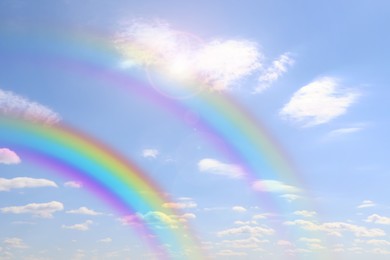 Image of Beautiful view of bright rainbows in blue sky on sunny day