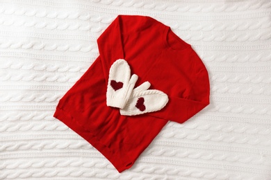 Red cashmere sweater and mittens on knitted plaid, top view