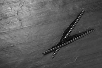 Photo of Car windshield wipers on black slate background, flat lay. Space for text