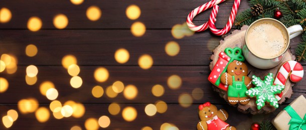 Decorated Christmas cookies and cup of delicious drink on wooden table, flat lay. Space for text