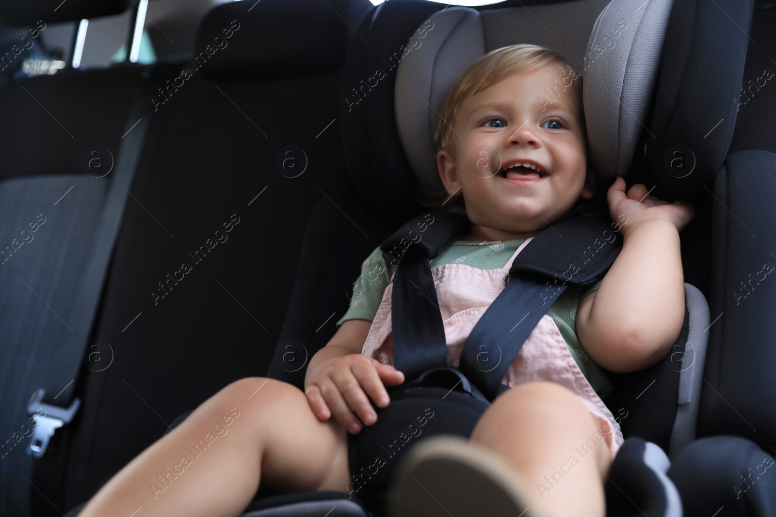 Photo of Cute little girl sitting in child safety seat inside car