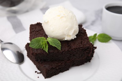 Tasty brownies served with ice cream and mint on table, closeup