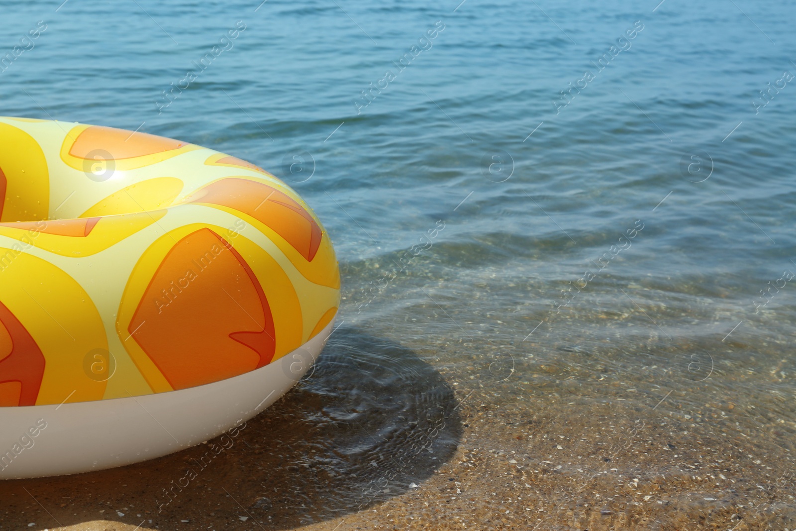 Photo of Bright inflatable ring floating on sea water. Space for text