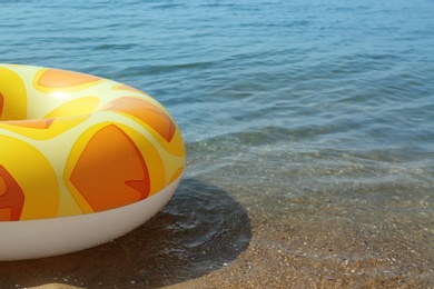 Photo of Bright inflatable ring floating on sea water. Space for text