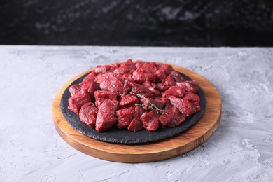 Photo of Pieces of raw beef meat and thyme sprigs on grey textured table