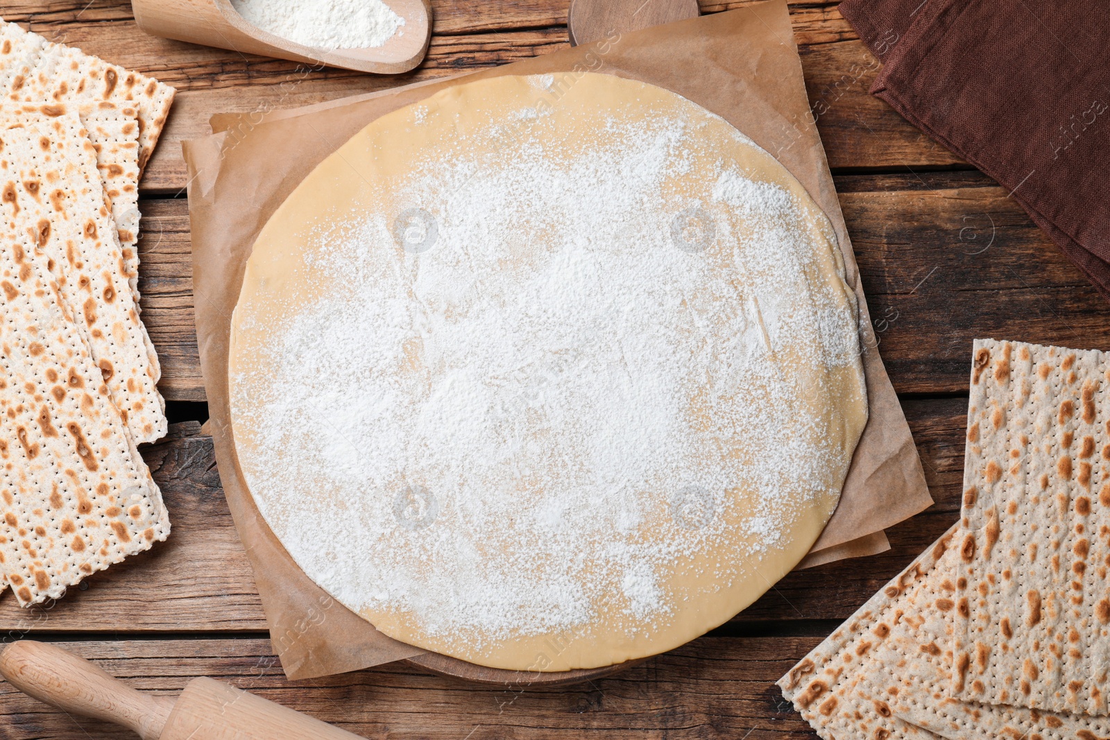 Photo of Matzos and raw dough on wooden table, flat lay