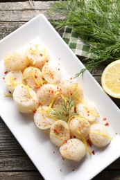Photo of Raw scallops with spices, dill and lemon zest on wooden table, flat lay
