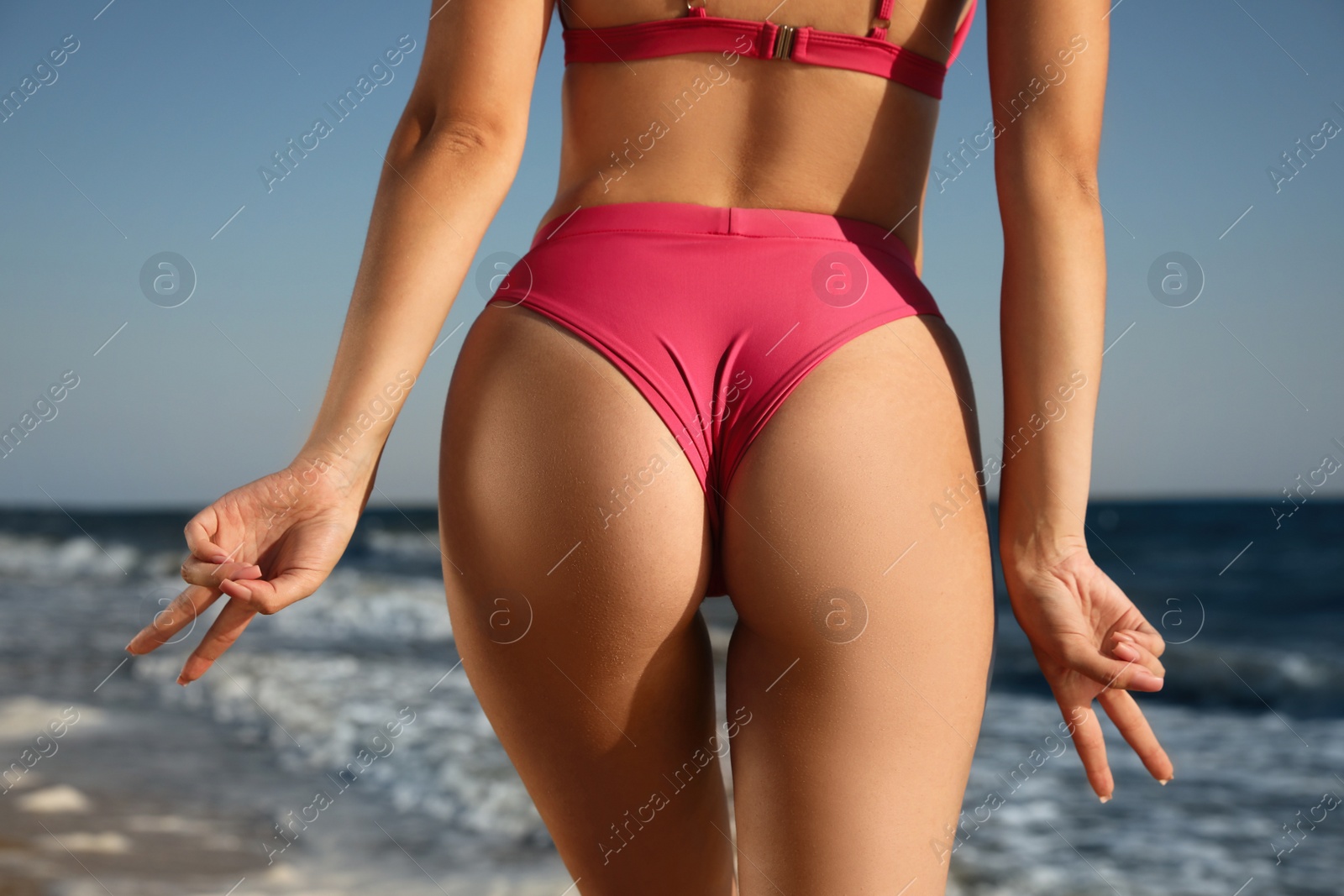Photo of Young woman with attractive body on beach, closeup. Back view