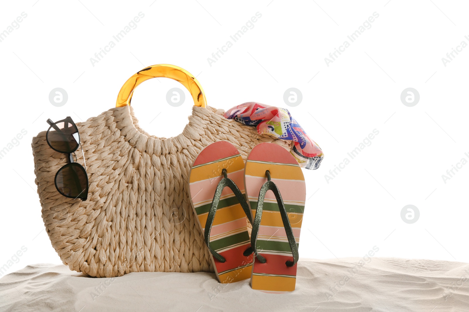 Photo of Stylish bag and beach accessories on sand against white background