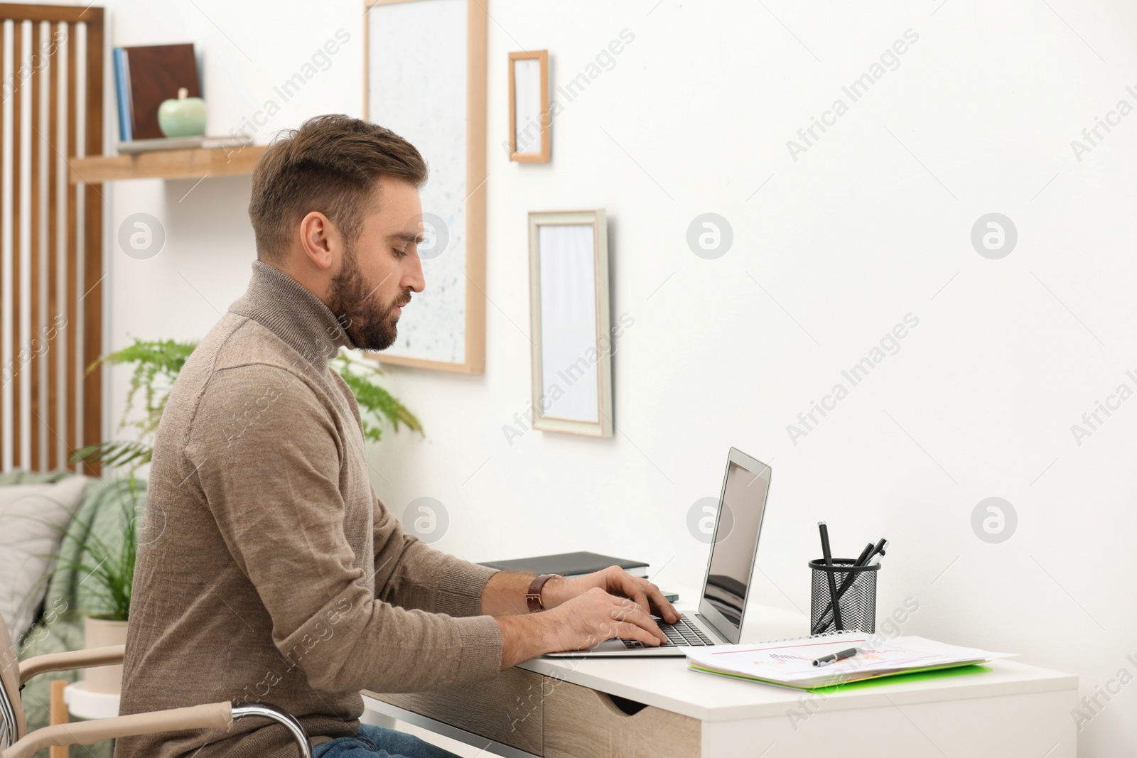 Photo of Young man working with laptop at home, space for text