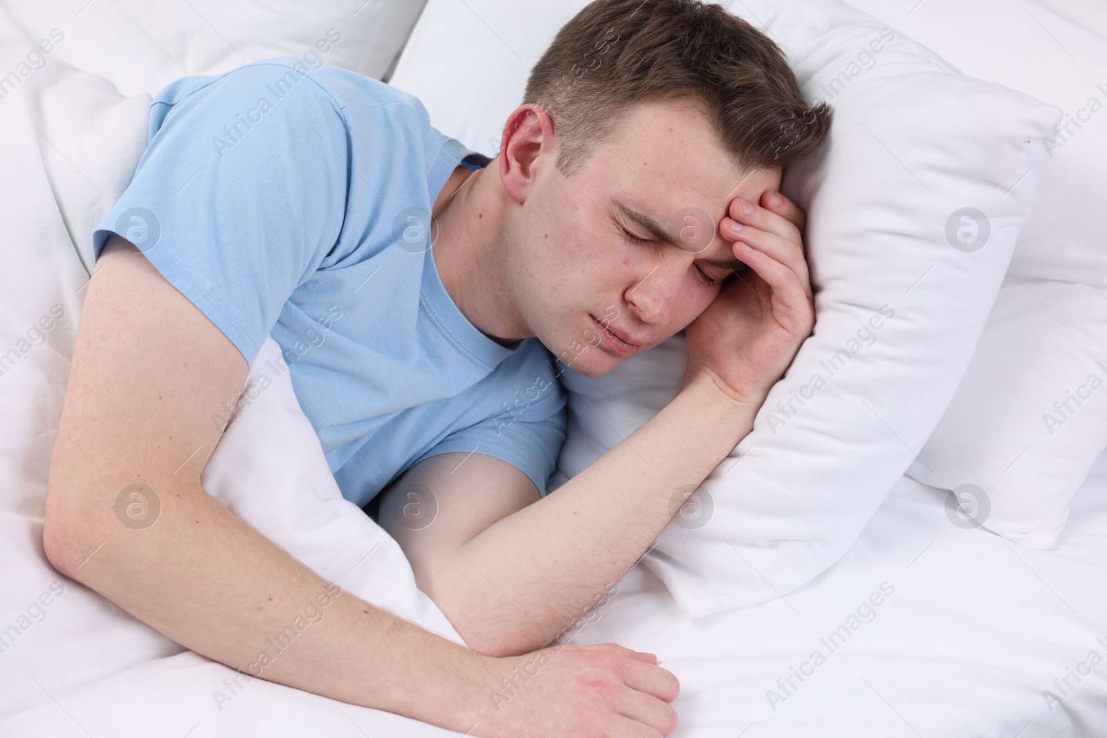 Photo of Sad man suffering from headache in bed indoors