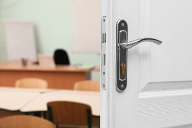 Image of Wooden door open into modern empty classroom