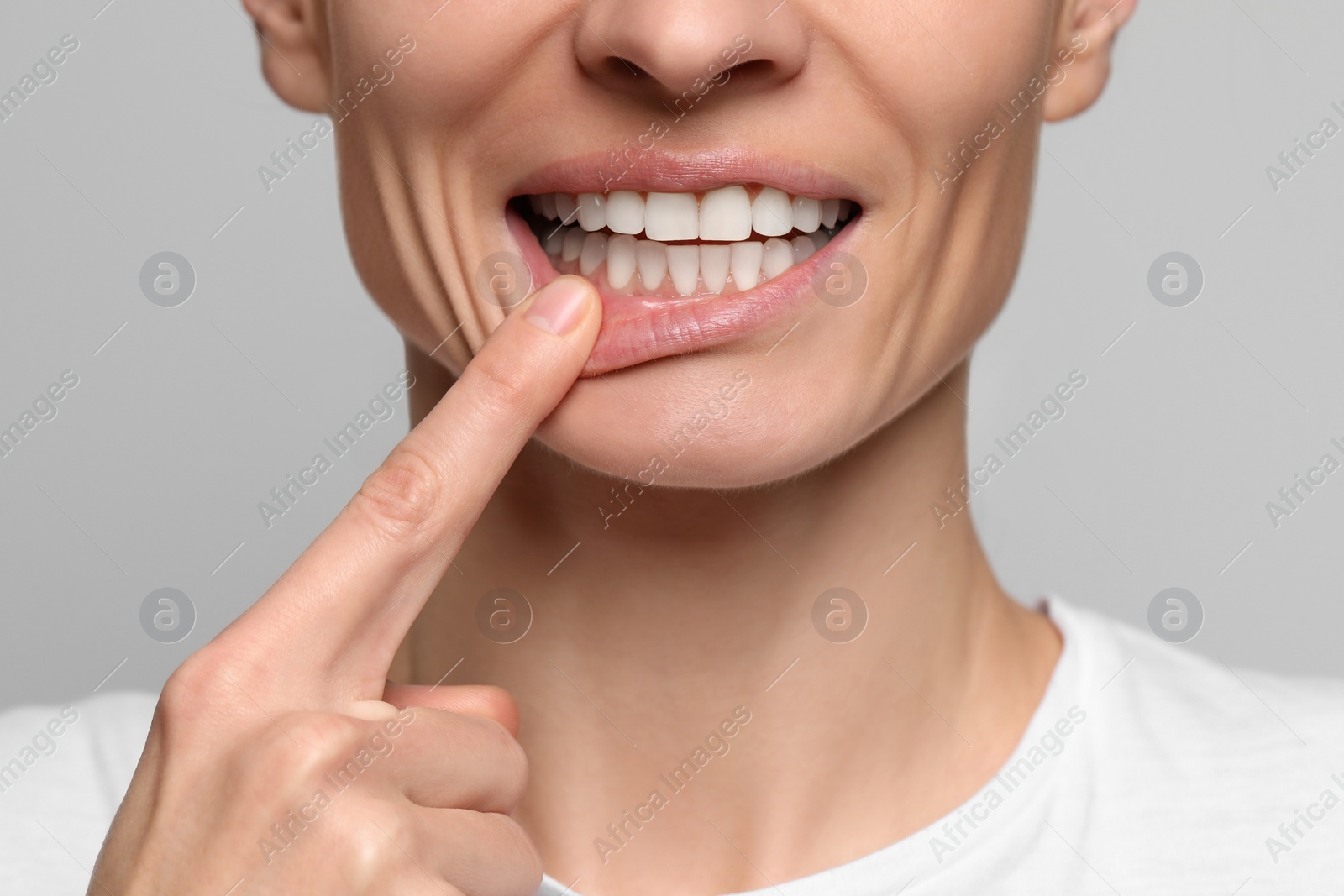 Photo of Woman showing healthy gums on light background, closeup