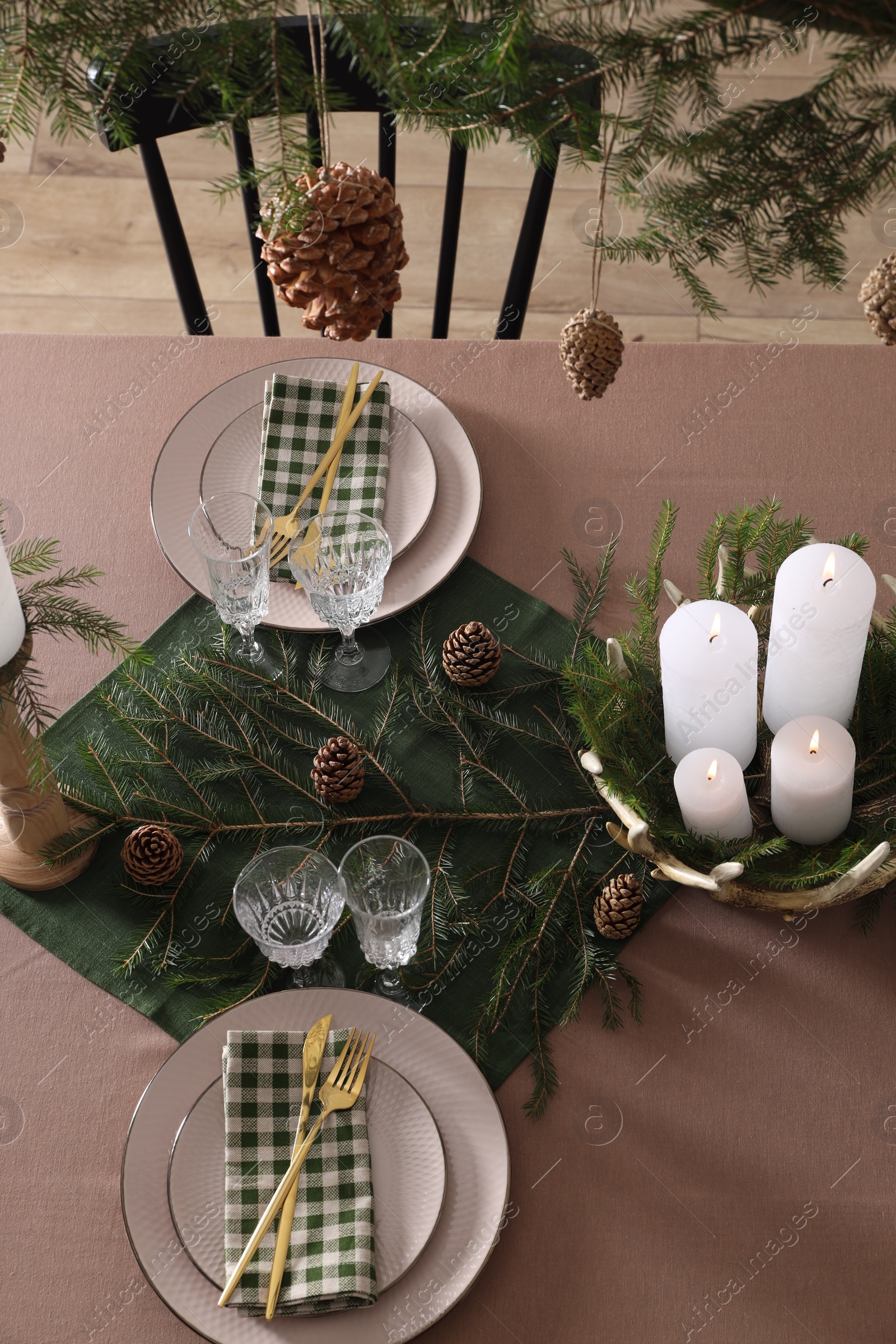 Photo of Christmas table setting with burning candles and other festive decor, above view