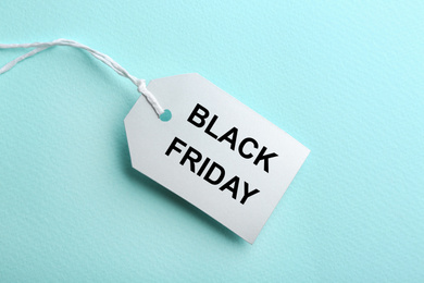 Blank tag on turquoise background, top view. Black Friday concept