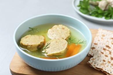 Photo of Board with bowl of Jewish matzoh balls soup on light table