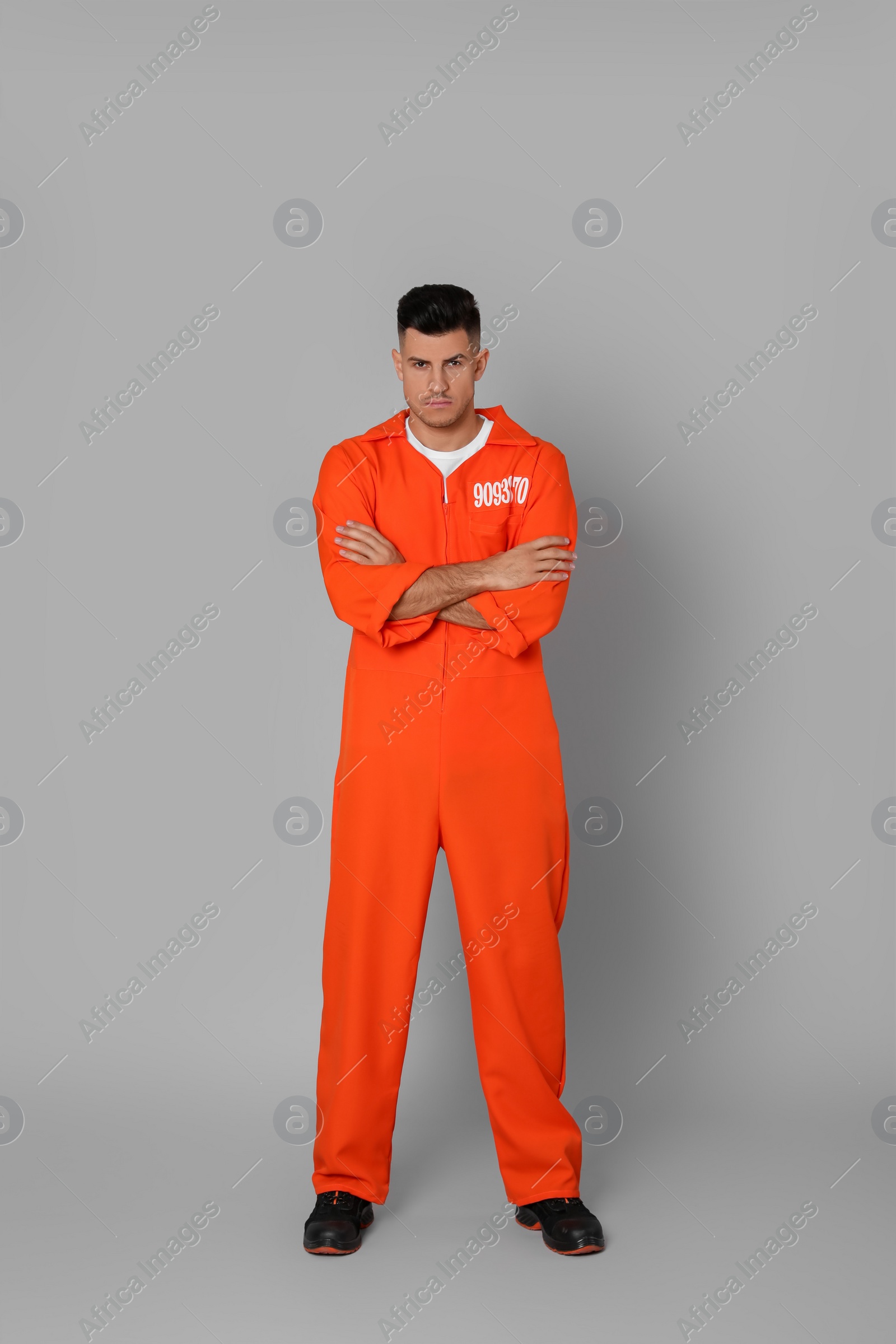 Photo of Prisoner in orange jumpsuit on grey background