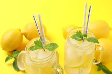 Natural freshly made lemonade with mint on yellow background, closeup. Summer refreshing drink