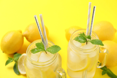 Photo of Natural freshly made lemonade with mint on yellow background, closeup. Summer refreshing drink