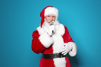 Photo of Santa Claus singing into microphone on color background. Christmas music