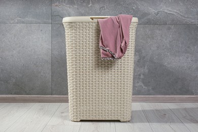 Laundry basket with clothes near grey wall