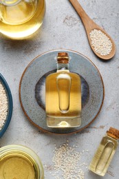 Photo of Sesame oil and seeds on light grey table, flat lay