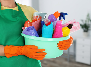 Image of Woman holding basin with cleaning supplies in office, closeup