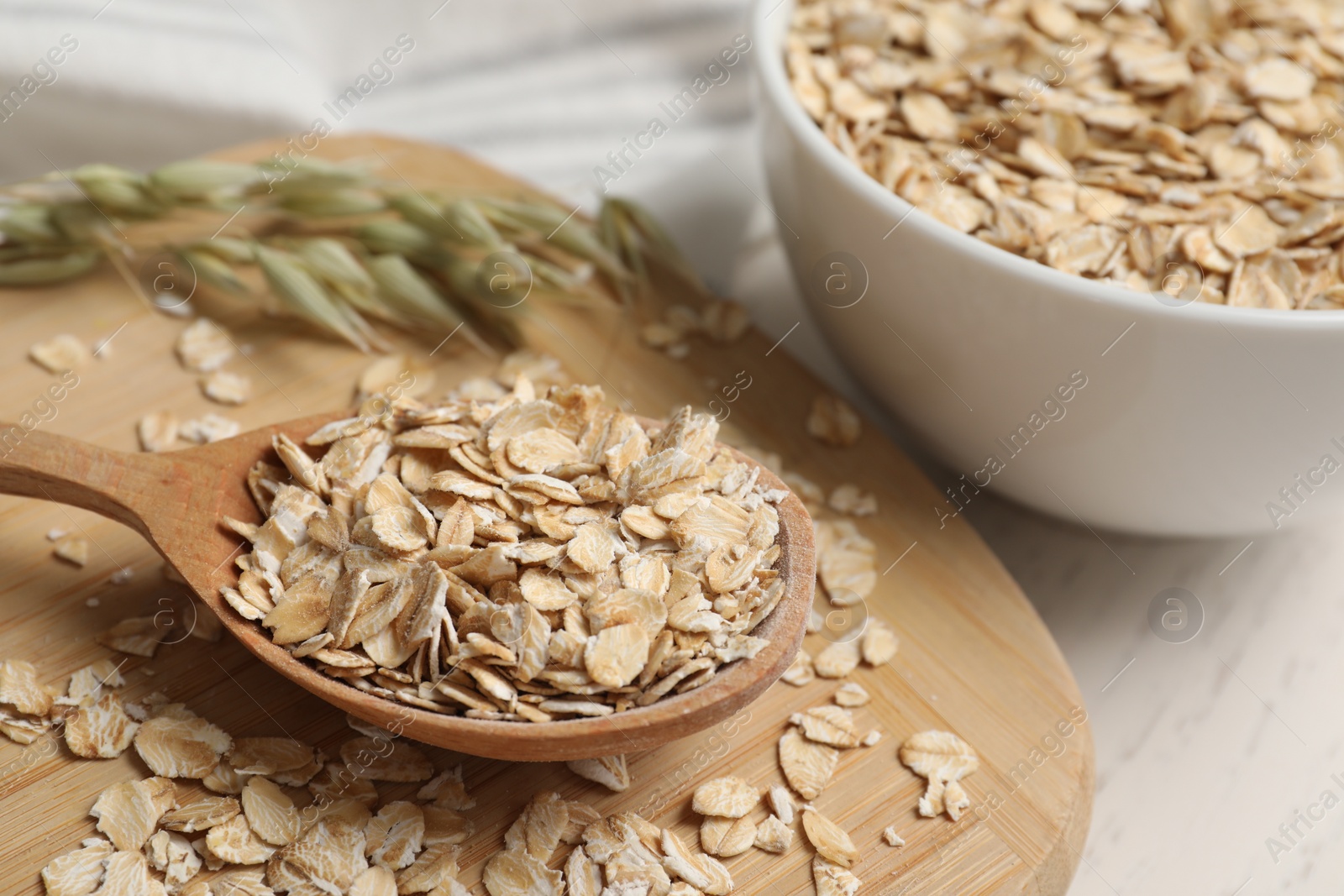 Photo of Wooden spoon with oatmeal on white table, closeup