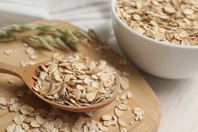 Photo of Wooden spoon with oatmeal on white table, closeup