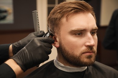 Professional hairdresser working with client in barbershop