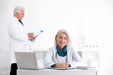 Portrait of mature female doctor in white coat at workplace